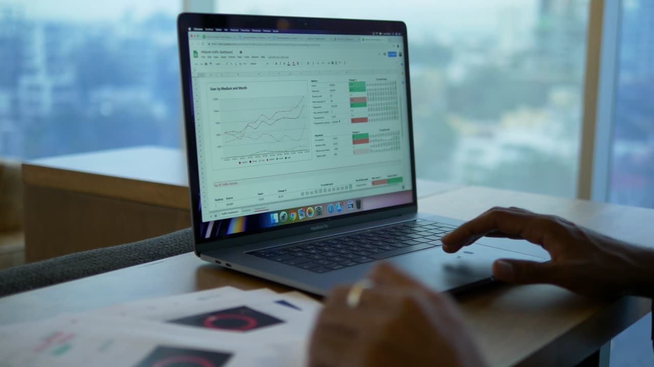 A laptop showing a financial spreadsheet beside a window