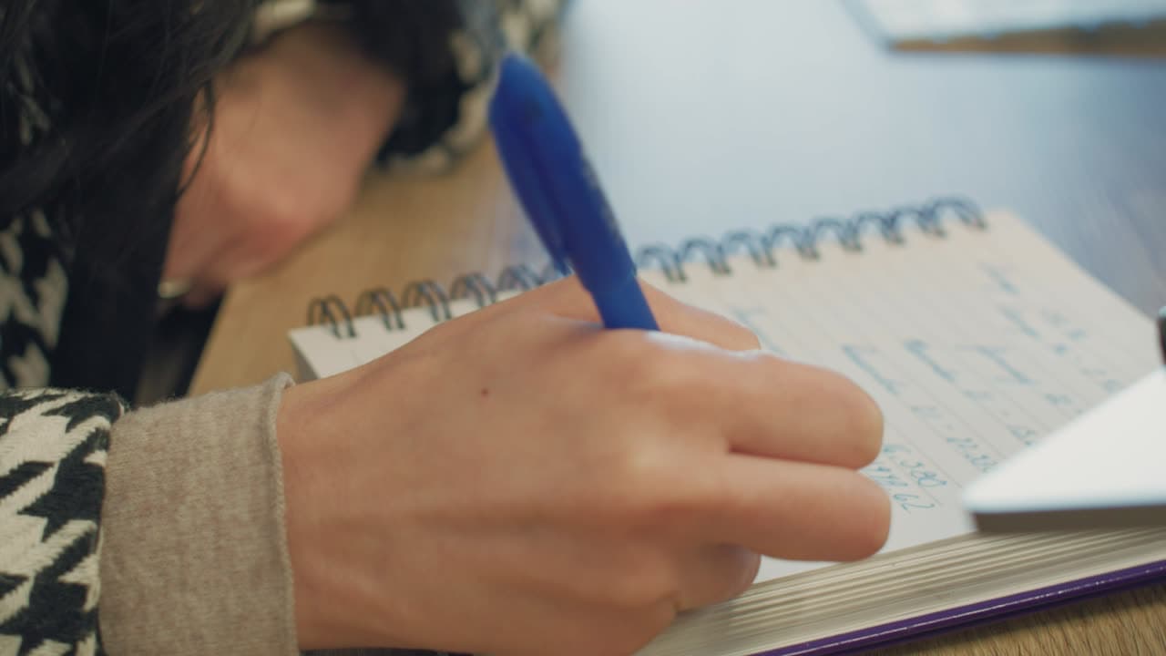 A business owner taking handwritten notes in a spiral notebook